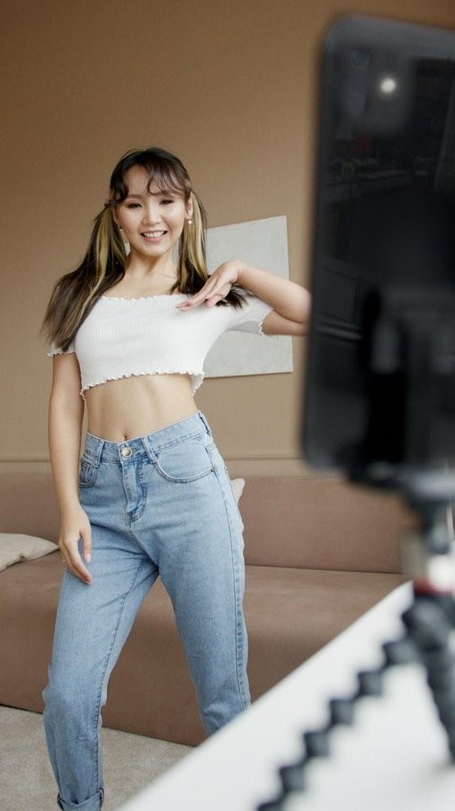 Young content creator filming a TikTok video using a smartphone and ring light